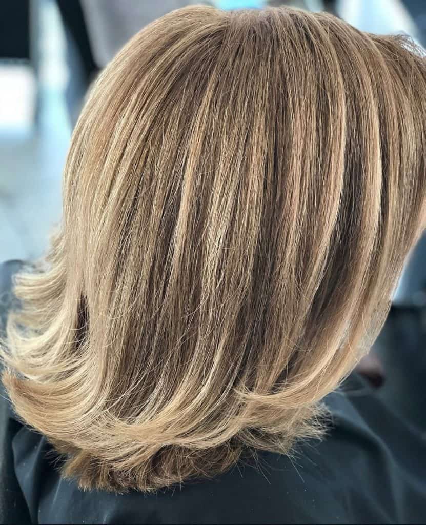 weibliche Kundin von der Seite mit mittellangem Haar mit blonder Balayage Farbtechnik